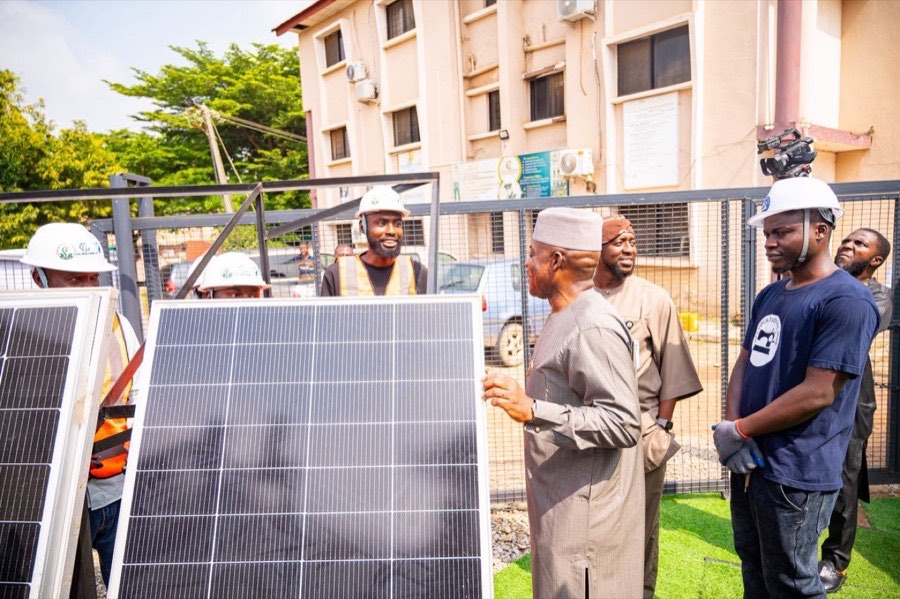 Young Nigerians in hard hats presenting solar panel installations